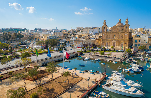 Aerial view of Msida marina bay and church. Sunny day, Maltese and Europe flags. Malta island