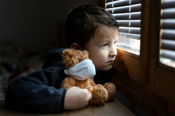 istock Small sad boy looking through the window during Coronavirus isolation. 1217131370