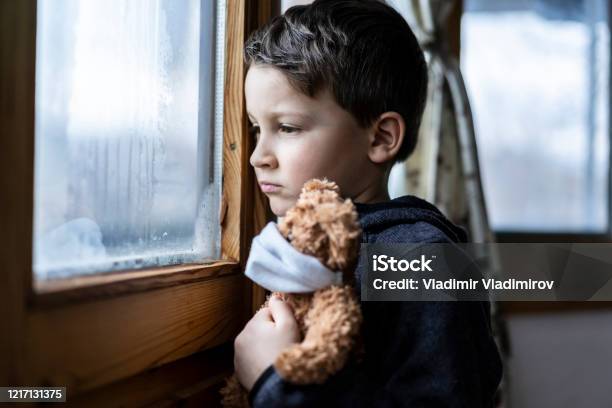 Kleiner Trauriger Junge Der Während Der Coronavirusisolation Durch Das Fenster Schaut Stockfoto und mehr Bilder von Kind