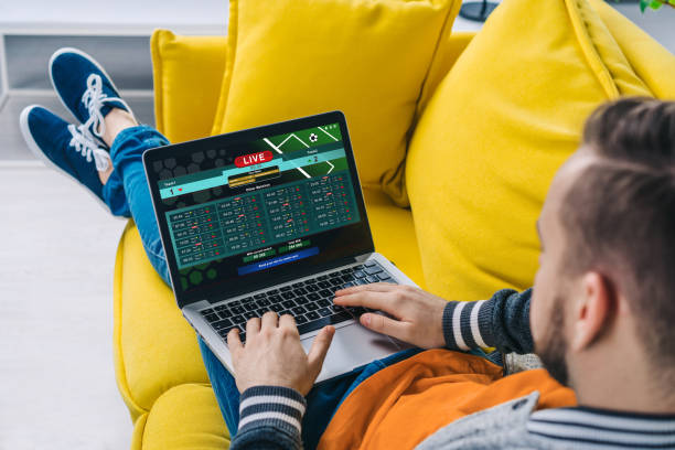 Cropped shot of a man lying on sofa making bets online at bookmaker's website using laptop Cropped shot of a man lying on sofa making bets online at bookmaker's website using laptop. best online bookmakers stock pictures, royalty-free photos & images