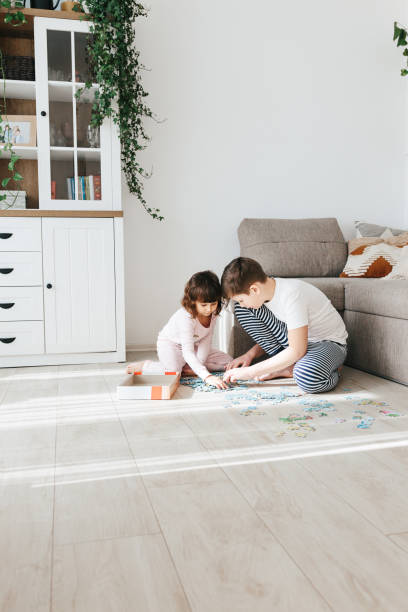 Brother and sister playing puzzles at home. Stay at home activity for kids. stock photo