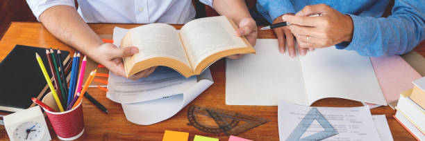 istock College tutor helps friend teaching and learning for a test or an exam catching up, education and school encouragement concept. 1217133101