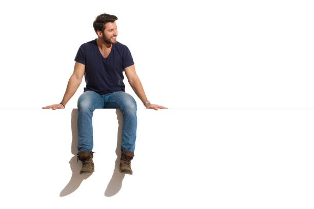 Smiling Handsome Man Is Sitting On A Top Of White Banner And Looking At The Side stock photo