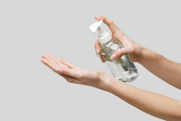 istock Female hands using hand sanitizer gel or liquid soap dispenser over light grey background 1217137442