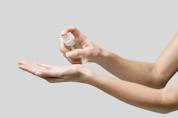 istock Female hands using hand sanitizer spray dispenser over light grey background 1217137466