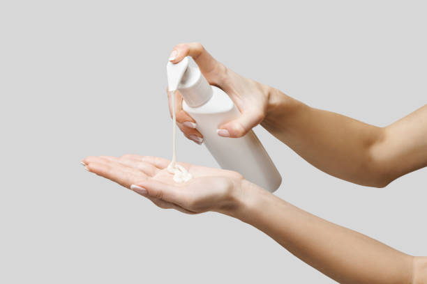 istock Female hands using hand sanitizer gel or liquid soap dispenser over light grey background 1217137567