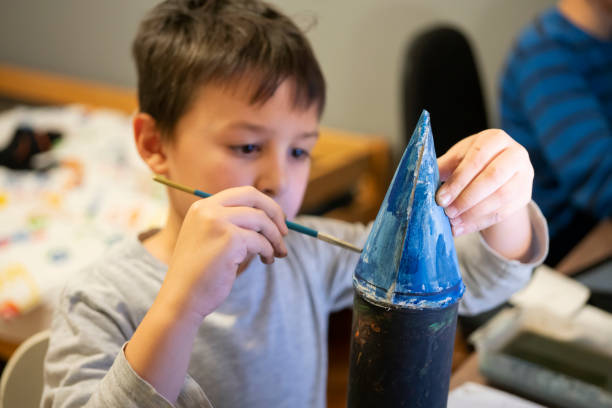 Elementary age school boy making space rocket Elementary age school boy making space rocket from recycle material model rocket stock pictures, royalty-free photos & images