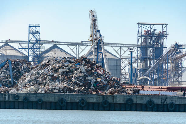 in port loading and unloading scrap metal on a barge with an excavator