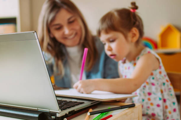 istock Toddler daughter drawing during watching online learnin 1217139839
