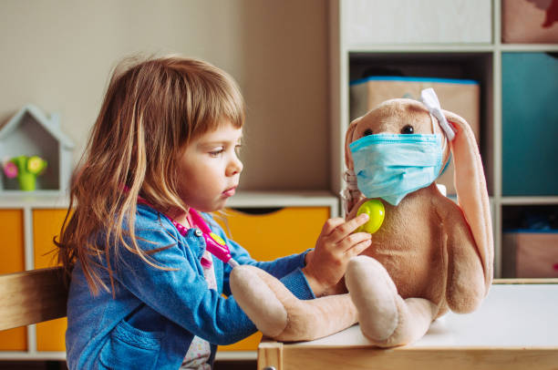 Little girl playing doctor using stethoscope toy Little girl playing doctor using stethoscope toy with rabbit soft toy in mask in the kids room sick bunny stock pictures, royalty-free photos & images