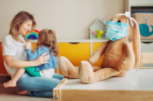 Soft toy bunny on the table in the kids room Soft toy bunny on the table in the kids room. Defocused toddler daughter playing with mother. Stay home during quarantine virus outbreak concept. animal related occupation photos stock pictures, royalty-free photos & images