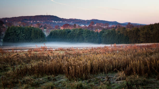 A foggy meadow with fall foliage decorating a series of hills in Berks County, PA stock photo