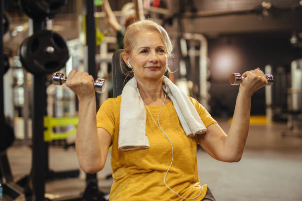 Senior woman working out with dumbbells at the gym Senior woman working out with dumbbells at the gym senior bodybuilders stock pictures, royalty-free photos & images