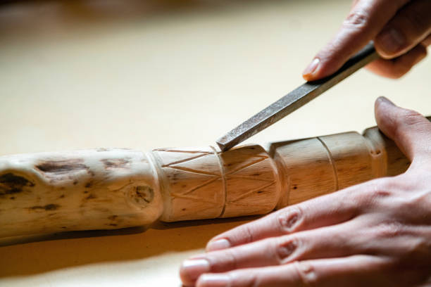 検疫中に木製の歩行棒を屋内で作る人のプロセス。ナイフを使ってテーブルの上に木の棒を彫る - cutting wood holding supporting ストックフォトと画像