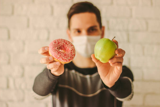 istock Sports man choosing between healthy apple or sugar donut 1217148570