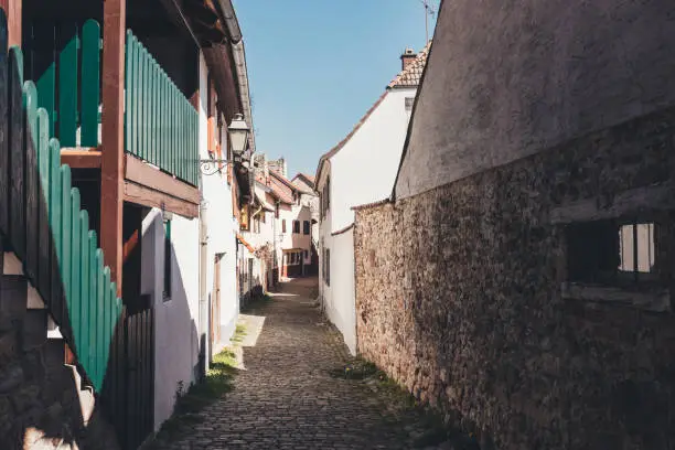 Narrow empty cobbled street in an old German town with houses on either side under a sunny blue sky in spring receding into the distance