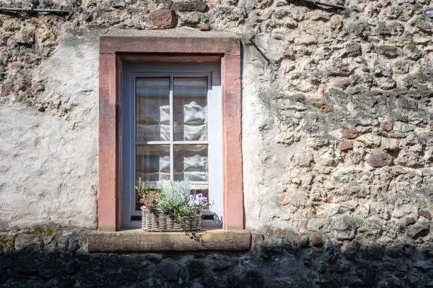 An old window on a wall with a basket of flowers in germany