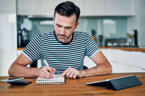 istock Handsome man at home and calculating home finance 1217156733