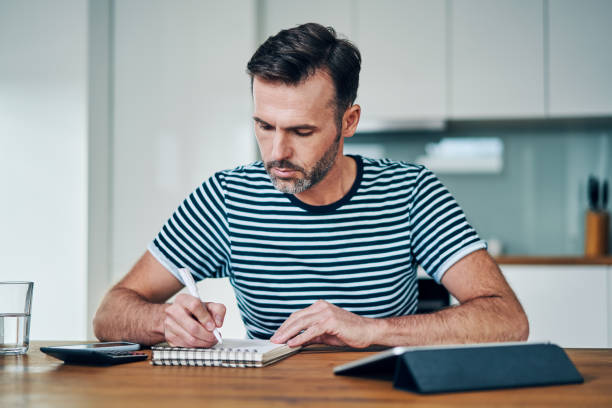 istock Thoughtful man writing in notebook while managing personal budget at home 1217156777