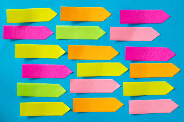 Colorful Empty Arrow-shaped sticky papers are on blue paper. Horizontal composition with copy space.