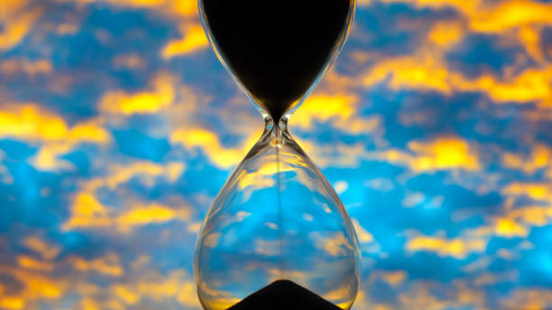 istock Hourglass against the sunset bright sky. Time and implementation of plans 1217158923