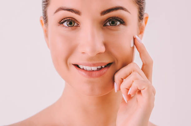 istock Girl applying moisturizing face cream on cheek 1217159357