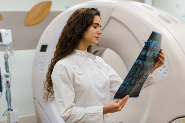 las jóvenes doctores en bata médica examinan la radiografía del cerebro del paciente después de la tomografía computarizada. diagnóstico por tomografía computarizada en clínica médica - cat scan abdomen medical scan x ray fotografías e imágenes de stock