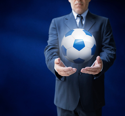 Businessman in suit offering soccer ball floating in the air