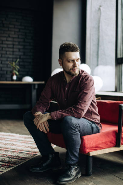 istock Young brutal man sitting on a chair 1217163376