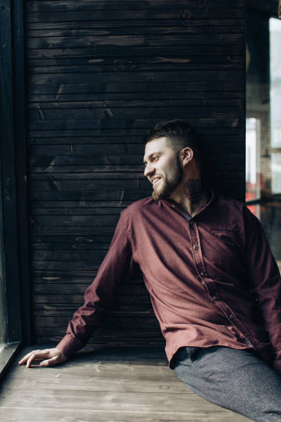 istock Young bearded man with tattoo on his neck smiling 1217163415