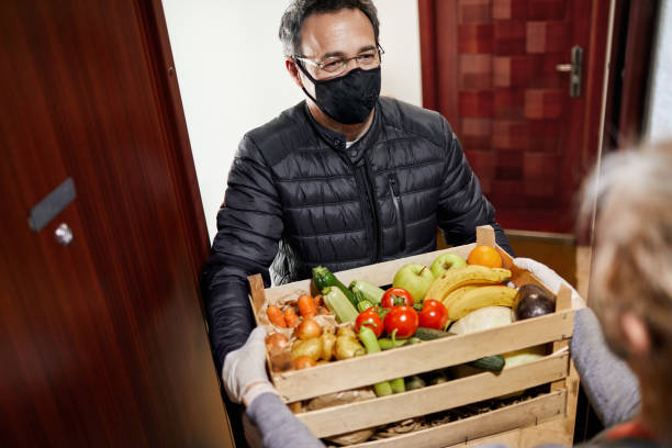 Delivering Food During Coronavirus Lockdown Man delivering fresh fruits and vegetables during coronavirus lockdown to elderly people. home delivery photos stock pictures, royalty-free photos & images