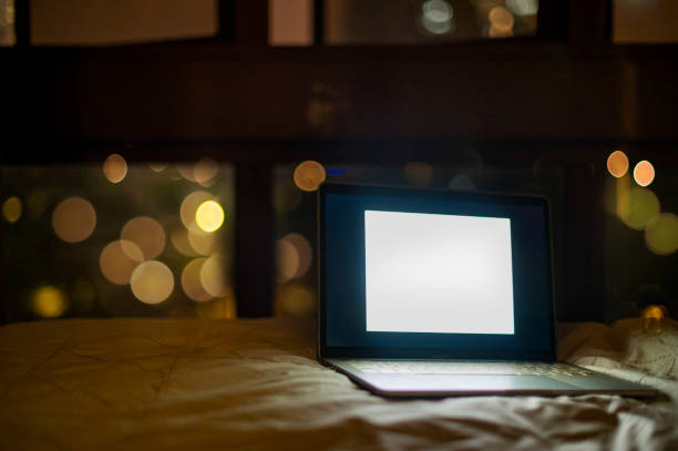 istock laptop on bed turn on with bokeh blur light image at the back through window at night 1217168462