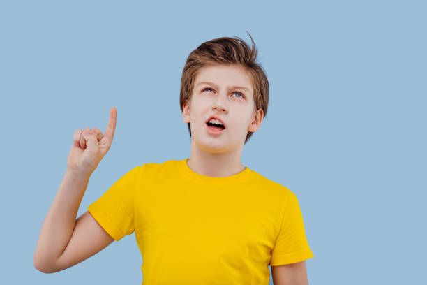 istock Confused cute schoolboy gesturing in studio on blue background 1217168613