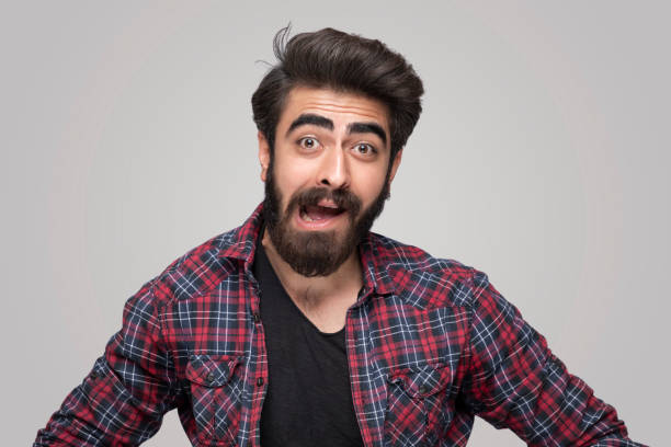 Portrait of shocking handsome man looking at camera over isolated gray background Portrait of shocking handsome man looking at camera over isolated gray background confusion raised eyebrows human face men stock pictures, royalty-free photos & images