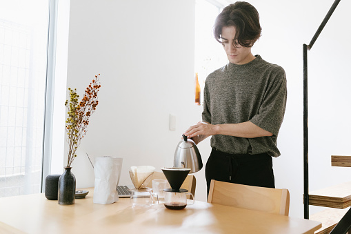 Young man making pour over coffee in the morning.