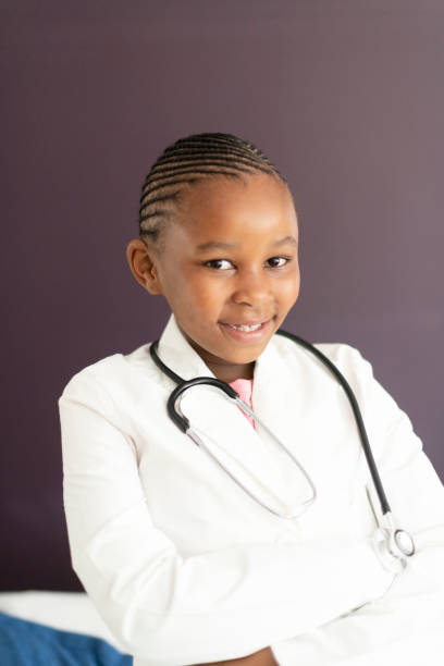 istock Young girl smiles to camera wearing doctors coat 1217172500