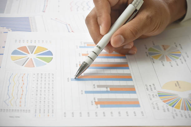 istock Businessman holding pen pointing analyzing business report with graph and chart on desk. 1217175752