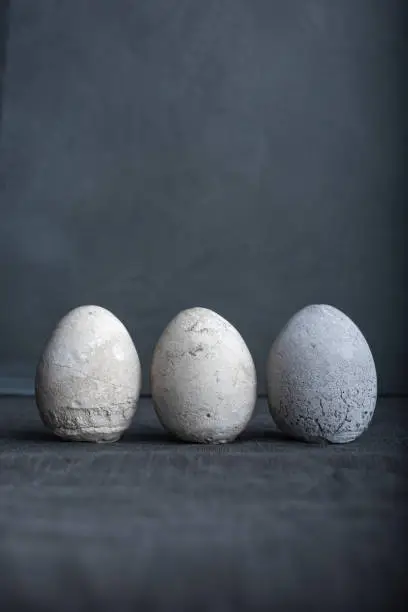 Group of concrete eggs still life on moody blue background