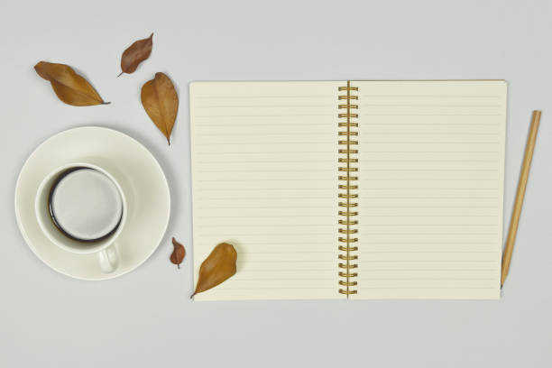 istock Cup of coffee and notebook with autumn leaves on white background. 1217175928
