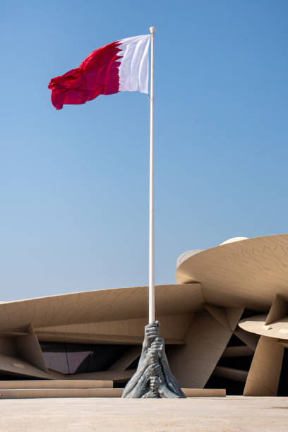 Qatari Flag and Qatar National Museum in Doha, Qatar Doha, Qatar - February 22, 2020: A sculpture and giant Qatari flag stand in front of the newly opened Qatar National Museum. qatar flag stock pictures, royalty-free photos & images