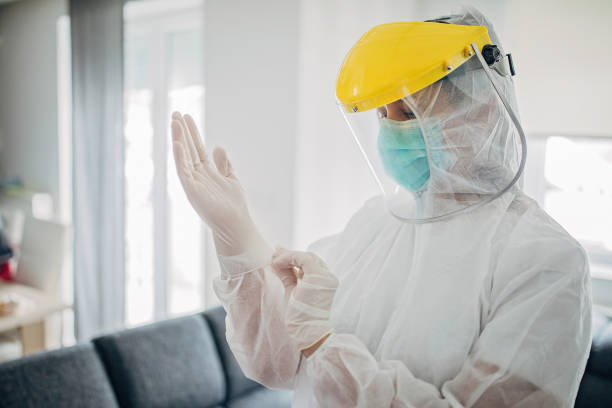 female doctor in full protective suit in home inspection - protective suit fotos imagens e fotografias de stock