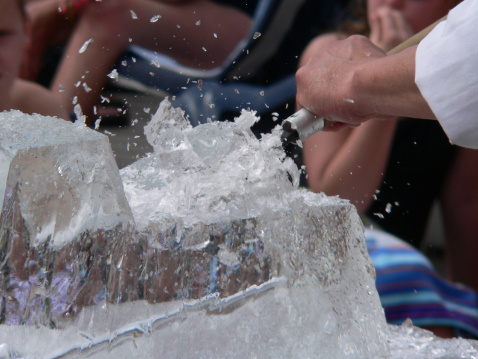 Ice sculpture being chiseled in front of out of onlookers