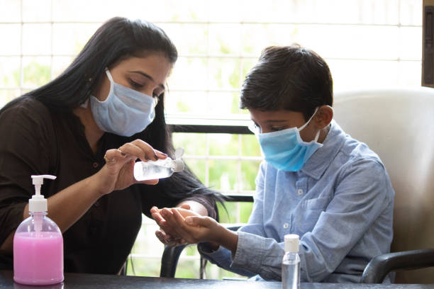 Mother pouring sanitizer on cupped hands of son Cautious woman teaching son how to clean hands with sanitizer and protect self from infectious covid-19 disease world health organization photos stock pictures, royalty-free photos & images