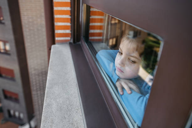 istock Sad girl looking out the window 1217179615
