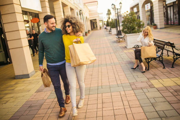 ショッピングバッグを歩いてショッピングを楽しむ美しい若いカップル - spending money adult african ethnicity bag ストックフォトと画像