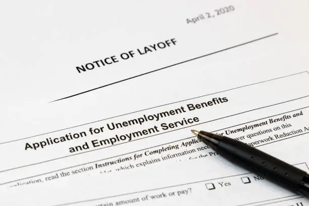 Photo of Job layoff notice and application for unemployment insurance benefits paperwork. Concept of Covid-19 coronavirus and stay at home order impact on economy