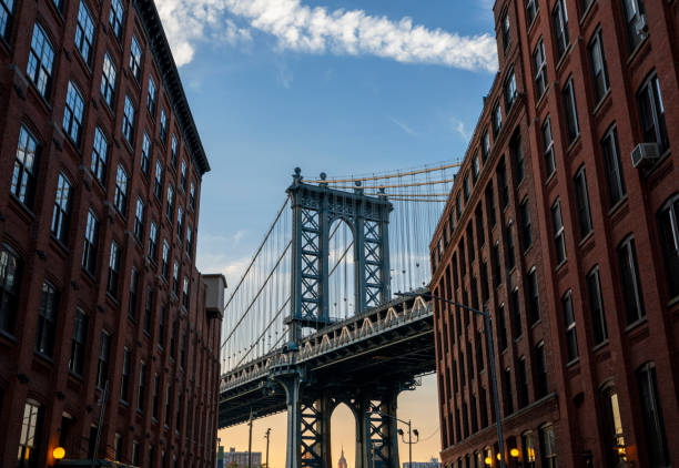 Manhattan Bridge steel structure framed by brick and concrete buildings in New York City. USA.