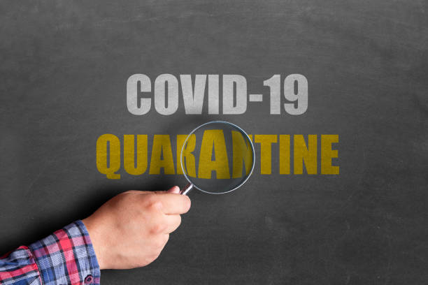 istock Man holding magnifying glass over coronavirus quarantine text on blackboard 1217182464