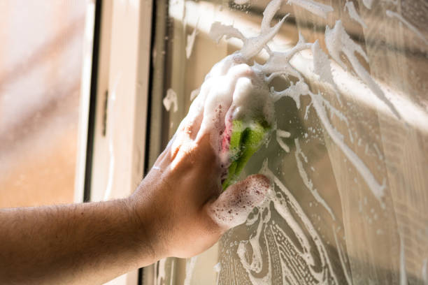 istock Man cleaning window using window cleaning squeegee and cleaning sprayer, cleaning services concept. Housework and housekeeping concept 1217182986