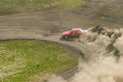 Rally car on a slide in a curve on a dusty racing track